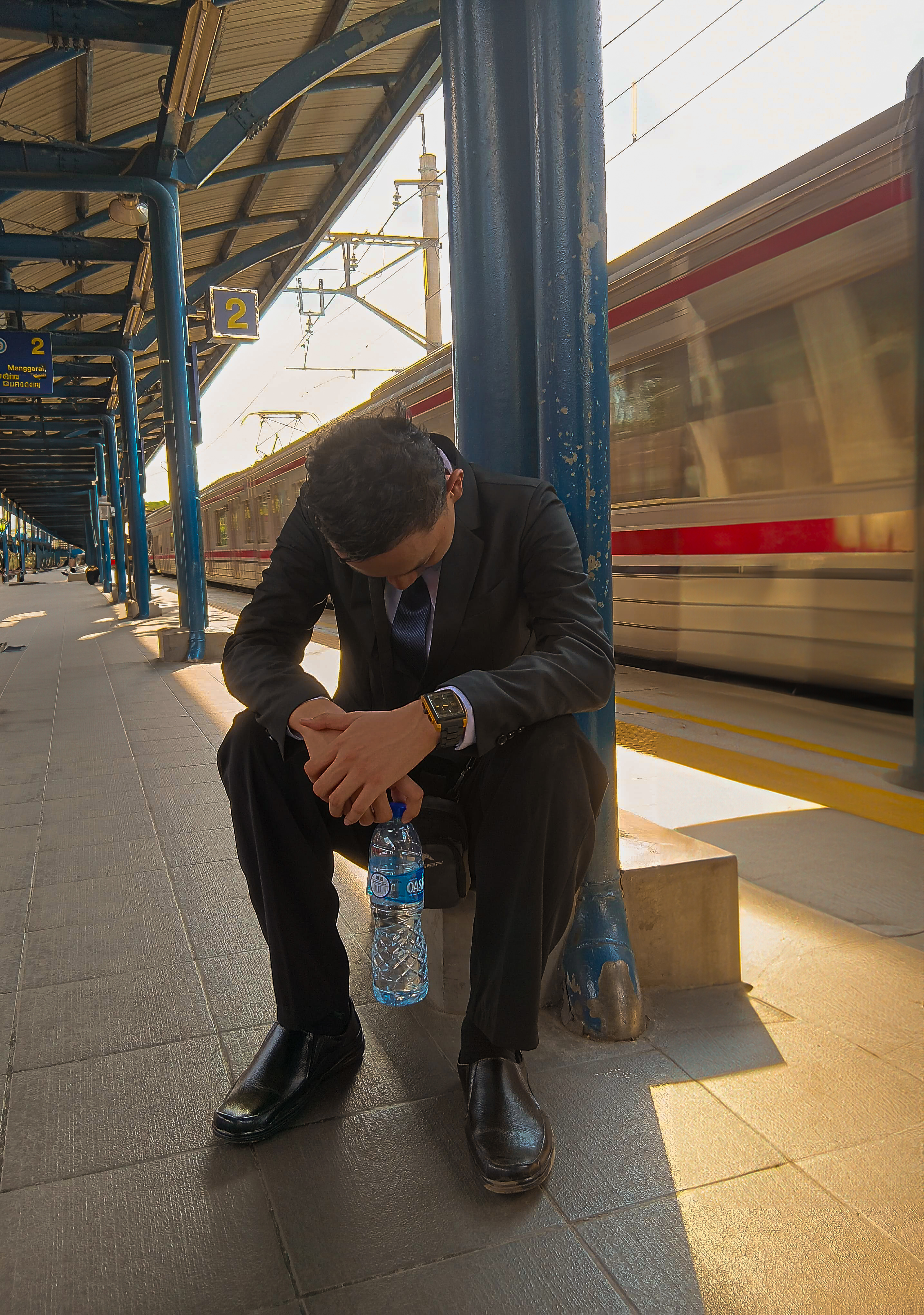 Romi wearing a suit while waiting at a train station